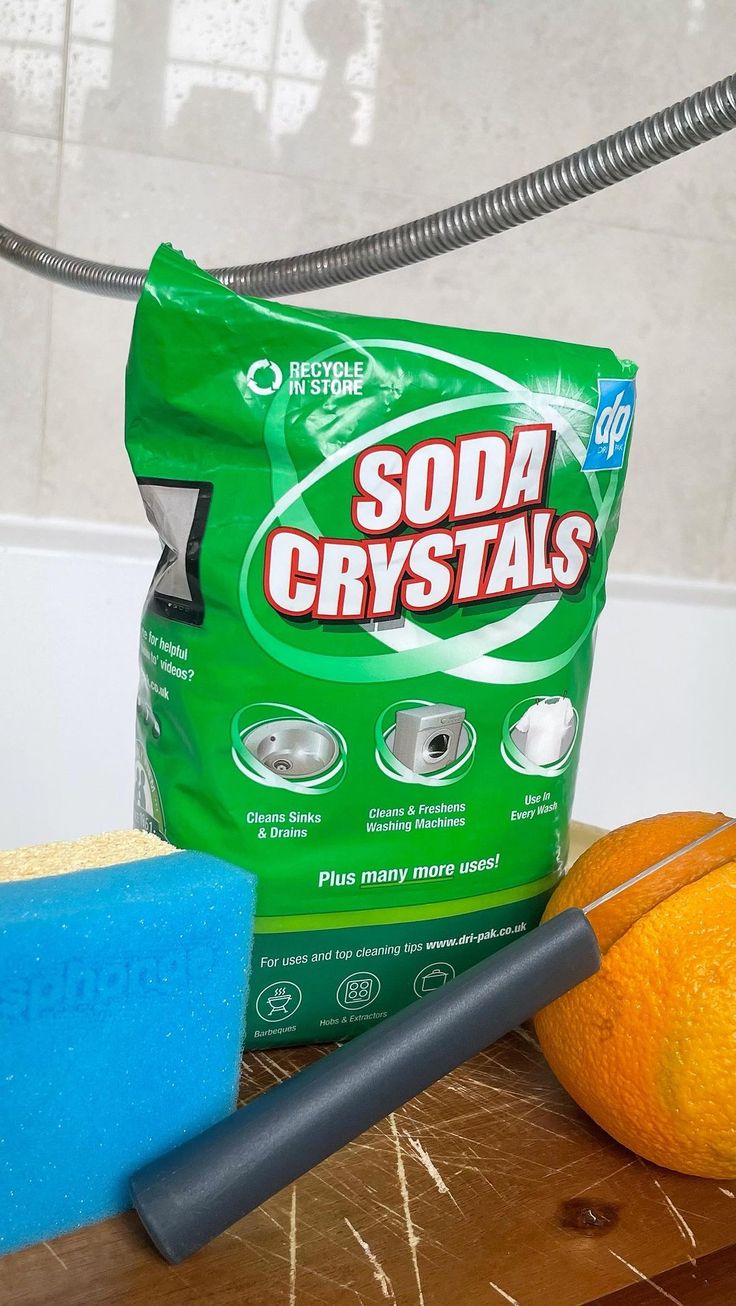 A Bag Of Soda Crystals Sitting Next To An Orange And A Sponge On A Table